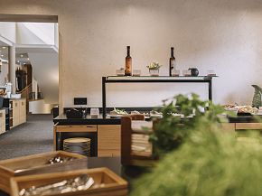 Gemütliches Buffet im Hotel Kaiser in Tirol mit Weinflaschen und frischen Kräutern.