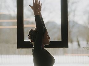 Woman practicing yoga in a serene room with mountain views.