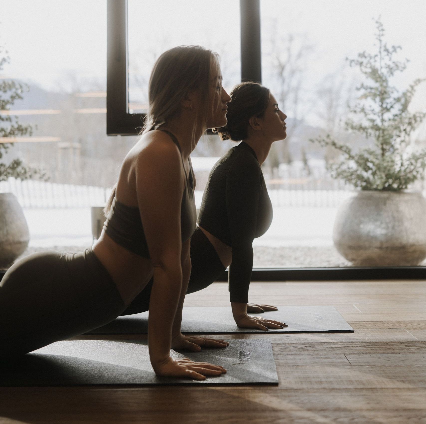Zwei Menschen entspannt bei einer Yoga-Session mit Blick auf verschneite Natur im Hotel Kaiser in Tirol.